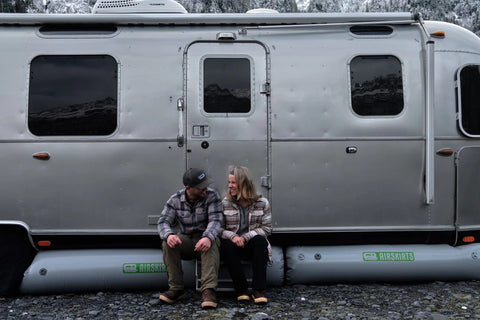 AIRSKIRTS Inflatable Trailer Skirt Kit - Couple Seated Outside Skirted Airstream in Winter | United RV Parts